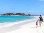 young father and his son walking at the perfect caribbean beach at middle caicos.